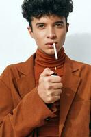 Hand Mann Porträt Mode Schüler Rauchen Sitzung Lebensstil nachdenklich Zigarette Beige foto