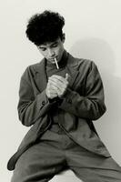 und Mann nachdenklich Hipster Sitzung Modell- Porträt Rauchen posieren Mode Weiß Zigarette schwarz Schüler foto