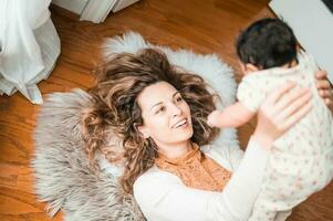 ein Frau ist halten ihr Baby während Verlegung auf das Fußboden foto