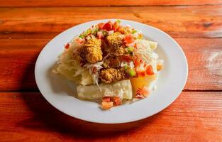 traditionell Chicharron Gericht mit Maniok und Tomate Salat. Latein Essen Chicharron con Yuca serviert auf hölzern Tisch. nicaraguanisch Gericht Chicharron mit Maniok auf das Tisch. foto