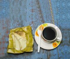 oben Aussicht von Tamal Pisque ausgestopft mit ein Tasse von Kaffee serviert auf das Tisch. Tamal Pisque ausgestopft typisch nicaraguanisch Lebensmittel. Aussicht von ein ausgestopft Tamale mit ein Tasse von Kaffee serviert auf ein hölzern Tabelle foto