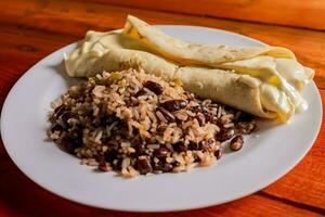 traditionell Gallo Pinto mit Quesillo serviert auf hölzern Tisch. nicaraguanisch galoppieren mit Quesillo auf das Tisch. typisch nicaraguanisch Lebensmittel foto