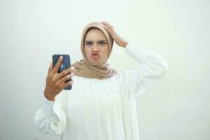 aufgeregt schön asiatisch Muslim Frau zeigen Handy, Mobiltelefon Telefon isoliert Über Weiß Hintergrund foto
