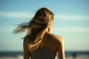 Rückseite Aussicht von ein schön jung Frau mit Haar im das Wind auf das Strand. ai generativ foto