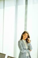 jung Frau mit Handy, Mobiltelefon Telefon durch das Fenster foto