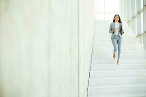 jung Geschäft Frau Gehen Nieder das Treppe und halten Laptop foto