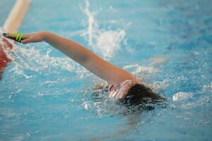 Kind Athlet schwimmt im das Schwimmbad. Schwimmen Abschnitt. foto
