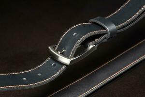 schwarz Leder Gürtel mit ein Metall Schnalle auf ein dunkel Hintergrund Nahansicht. foto