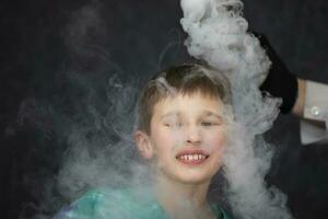 das Kind ist ein Teilnehmer im wissenschaftlich Experimente. ein Junge im Flüssigkeit Stickstoff- Rauch. foto