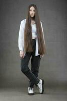 schön Brünette Mädchen mit sehr lange Haar auf ein grau Hintergrund. foto