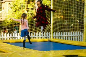 zwei wenig Mädchen Springen auf ein Trampolin beim ein Herbst Messe foto