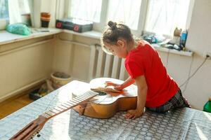 wenig Mädchen halten ein gebrochen Gitarre, Gitarre Reparatur foto