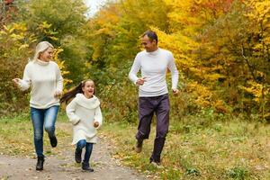 Bild von schön Familie im Herbst Park, jung Eltern mit nett bezaubernd Tochter spielen draußen, haben Spaß auf Hinterhof im fallen, glücklich Familie genießen herbstlich Natur foto