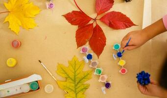 süß wenig Mädchen Färbung ein natürlich Kegel Tanne zu erstellen ein Blume, einstellen von Bürsten, malt, natürlich Herbst Materialien, erstellen Spaß und einfach mit Kinder, DIY zum Kindergarten foto