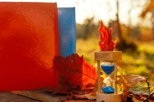 Herbst Zeit Thema, Sanduhr auf gefallen Blätter im verschiedene Farben mit Kopieren Raum. foto