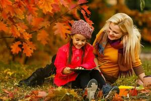 jung schön Mutter und ihr wenig Tochter im das Herbst Park foto