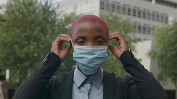 Porträt einer jungen Frau, die eine schützende Gesichtsmaske aufsetzt foto