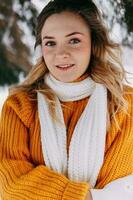 Teen blond im ein Gelb Sweatshirt draußen im Winter. ein Teenager Mädchen auf ein gehen im Winter Kleider im ein schneebedeckt Wald foto