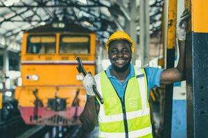 glücklich afrikanisch schwarz Arbeiter Ingenieur männlich Arbeiten schwer Industrie Zug Lokomotive Bedienung Mitarbeiter lächelnd Porträt. foto