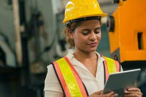 glücklich afrikanisch amerikanisch Frau Ingenieur Arbeiter Supervisor suchen beim Tablette Computer zu Steuerung arbeiten Bearbeitung im schwer Industrie Fabrik. foto