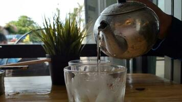 Gießen Wasser in ein Glas von Eis im ein Kaffee Geschäft. foto