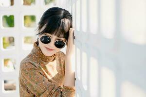 asiatisch Teen warnen runden Sonnenbrille im Jahrgang Stil Kleid Sommer- Mode Sammlung Modell- Porträt. foto