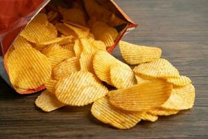 Kartoffelchips, leckeres Grillgewürz würzig für Crips, dünne Scheiben frittierter Snack Fast Food im offenen Beutel. foto