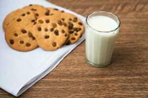 duftende, leckere, hausgemachte Kekse mit Rosinen und einem Glas frischer Milch auf dem weißen Küchentuch foto