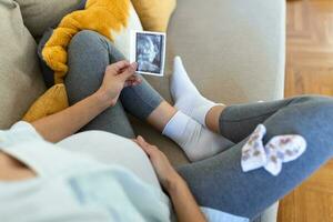 schwanger Frau halten Ultraschall Bild. Konzept von Schwangerschaft, Gesundheit Pflege, Gynäkologie, Medizin. jung Mutter warten von das Baby. Nahaufnahme, Kopieren Raum, drinnen. foto