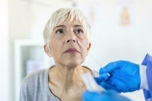 Fachmann medizinisch Arbeiter tragen persönlich schützend Ausrüstung testen Senior Frau zum gefährlich Krankheit mit Prüfung Stock foto