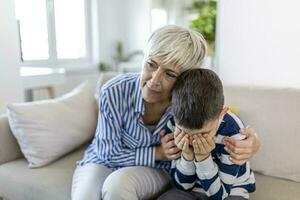 liebend Verstehen alt Oma Umarmen wenig Weinen Junge wohltuend verärgert Enkel, Senior Pflege Oma umarmen Kind tröstlich Kind im Tränen, Omas Empathie Unterstützung zum Enkel foto