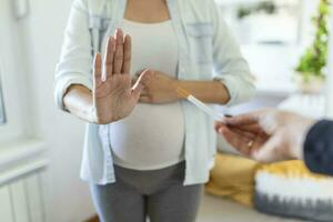 Rauchen und Schwangerschaft. schwanger Mädchen ablehnen zu nehmen Zigarette gestikulieren stoppen. schwanger Frau mit Bauch weigert sich passiv Rauchen. das Konzept von das Ablehnung von Schlecht Gewohnheiten foto