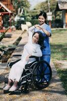 junge asiatische physiotherapeutin, die mit einer älteren frau beim gehen mit einer gehhilfe arbeitet foto