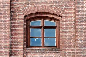 Ein gewölbtes Glasfenster an der alten roten Backsteinmauer foto