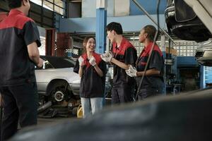 männlich Fachmann Supervisor Ingenieur und Mechaniker Arbeitskräfte sind heiter mit fertig Reparatur arbeiten, Zusammenarbeit Erfolge beim Auto Bedienung Garage, und harmonisch Instandhaltung Arbeitsplätze im Automobil Industrie. foto