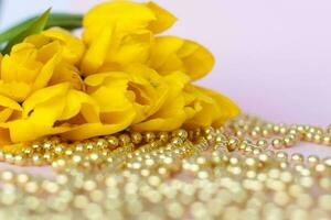 ein Strauß von frisch Gelb Tulpen. ein Strauß von Tulpen auf ein Rosa Hintergrund mit ein Streuung von Gold Perlen. Frühling Blumen im das Innere. das Konzept von Frühling oder Urlaub, März 8, International foto