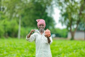 indisch Farmer halten gullak im Hand, Speichern Konzept, glücklich Arm Farmer foto