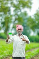 indisch glücklich Farmer halten leeren Flasche im Hände, glücklich Farmer zeigen Weiß Flasche foto