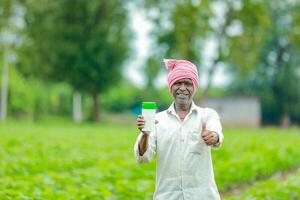 indisch glücklich Farmer halten leeren Flasche im Hände, glücklich Farmer zeigen Weiß Flasche foto