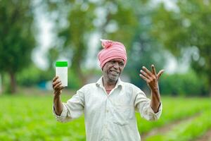 indisch glücklich Farmer halten leeren Flasche im Hände, glücklich Farmer zeigen Weiß Flasche foto