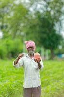 indisch Farmer halten gullak im Hand, Speichern Konzept, glücklich Arm Farmer foto