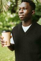 jung afrikanisch Mann halten Einweg Papier Kaffee Tasse auf Straße foto