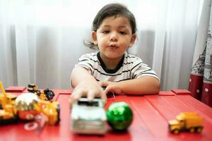 Baby Junge spielen mit Auto Spielzeuge lehrreich und kreativ Spielzeuge und Spiele zum jung Kinder. Kind beim Zuhause auf das Boden. foto