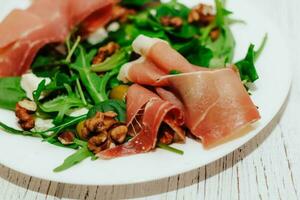 Stücke von getrocknet Schweinefleisch Jamon Prosciutto mit Rosmarin auf ein schwarz Tafel foto