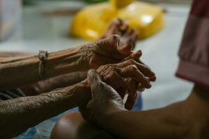 das Hand von ein Alten Person Wer schüttelt Hände mit ein jung Mann mit warm Besorgnis, Sorge es war ein Familie besuchen. Traditionen von das thailändisch Menschen foto