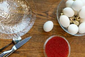 oben Aussicht von ein Schüssel von gekocht Eier und rot Kaviar auf hölzern Tisch, Heide Frühstück Mahlzeit foto
