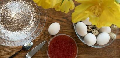 oben Aussicht von ein Schüssel von gekocht Eier und rot Kaviar auf hölzern Tisch, Heide Frühstück Mahlzeit foto