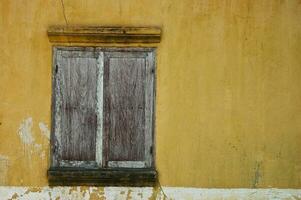 alt hölzern Fenster. mit ein Gelb Hintergrund foto