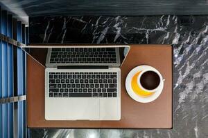 Büro Schreibtisch mit Laptop, Kaffee, oben Aussicht mit Kopieren Raum. foto