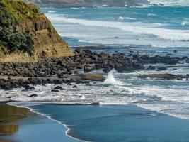 Wellen stürzen am Strand von Muriwai, Auckland, Neuseeland